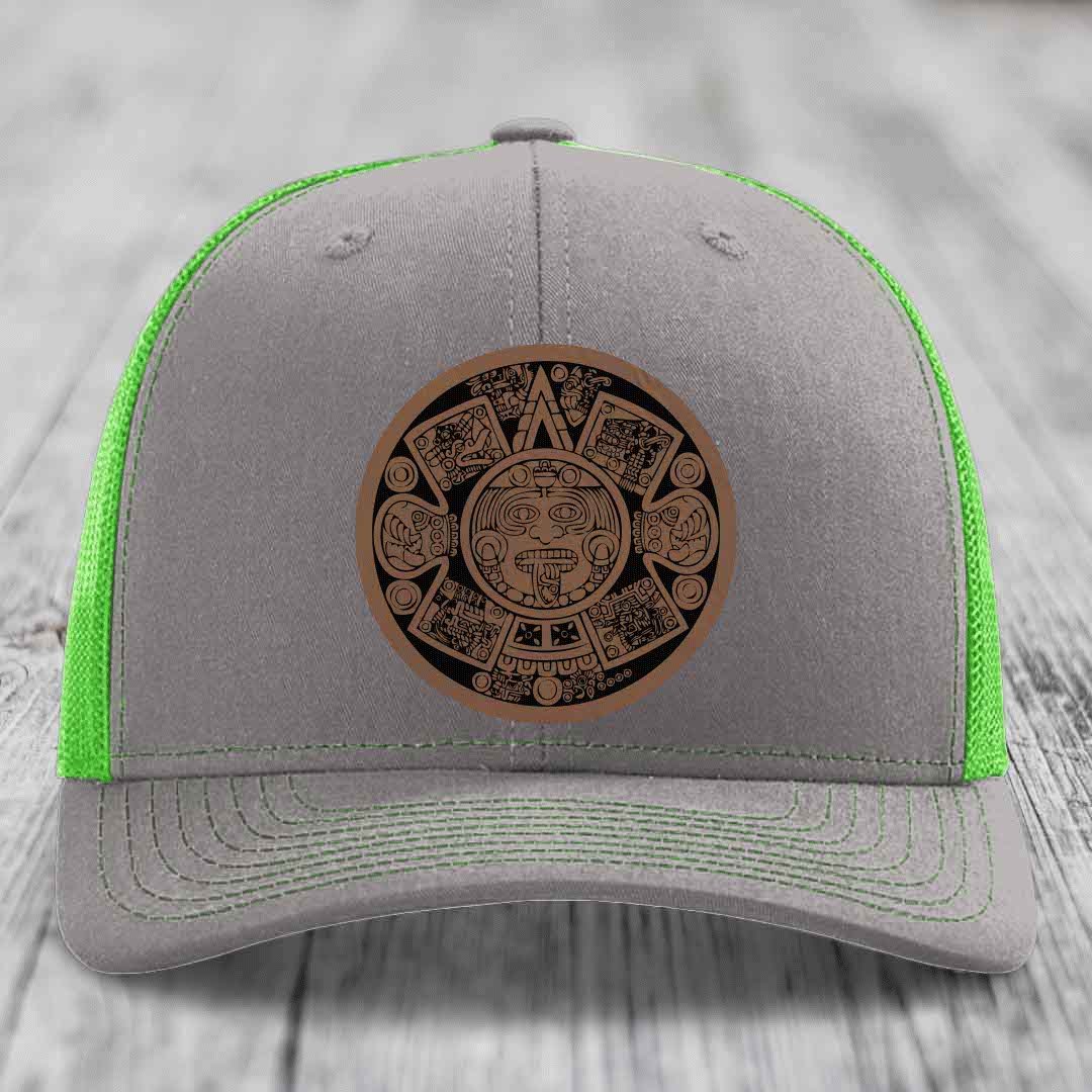 Grey trucker hat with neon green mesh and stitching, featuring a brown Aztec calendar leather patch on front.