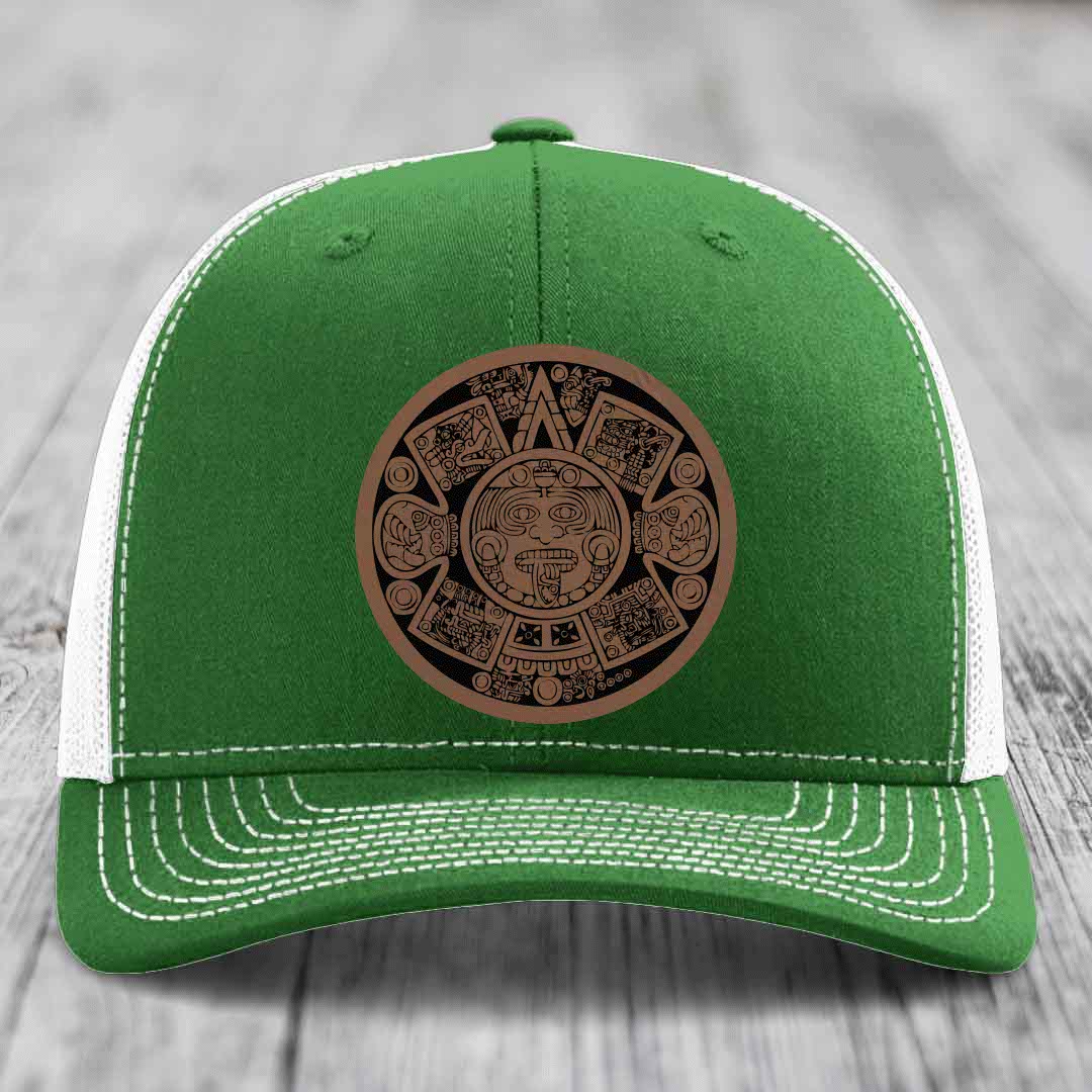Green trucker hat with white mesh back and brown Aztec calendar leather patch on front.