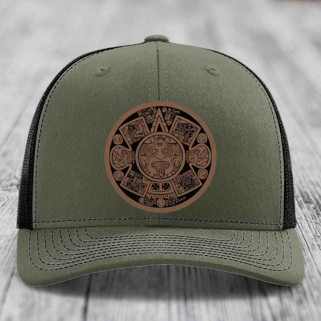 Olive green trucker hat with brown Aztec calendar leather patch on front.