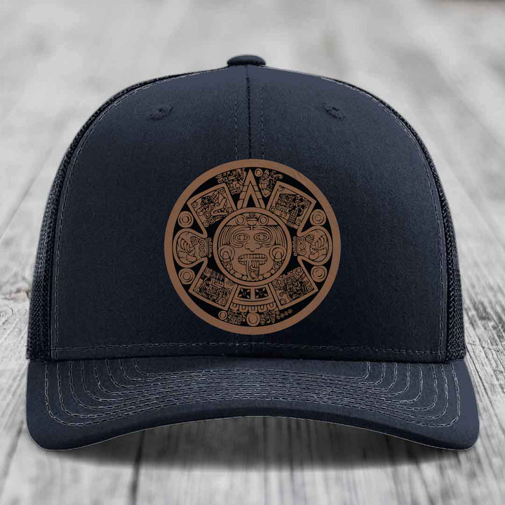 Black trucker hat with brown Aztec calendar leather patch on front.