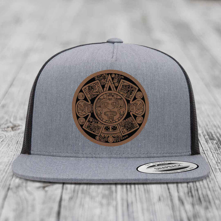 Grey trucker hat with brown Aztec calendar leather patch on front.