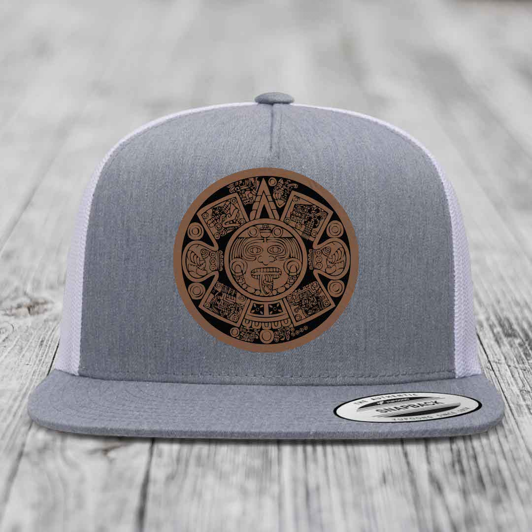Grey trucker hat with brown Aztec calendar leather patch on front.