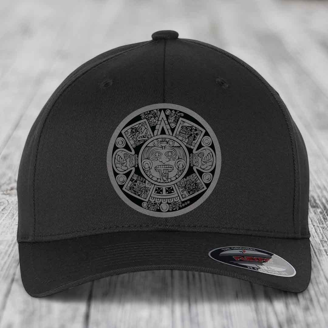 Black baseball cap with Aztec calendar design on front, displayed on wooden surface.