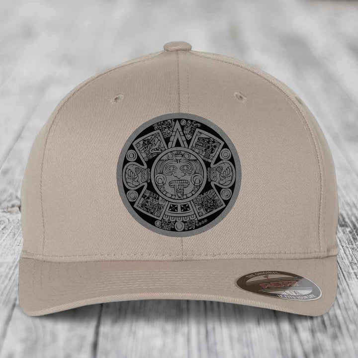 Beige baseball cap with Aztec calendar patch on front, featuring intricate black and gray design.
