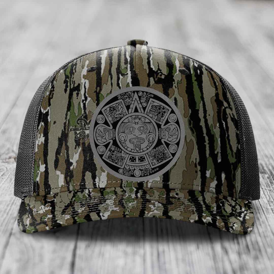 Camouflage trucker hat with Aztec calendar patch on front, black mesh back.