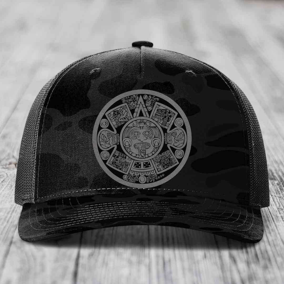Black camouflage trucker hat with Aztec calendar patch on front.