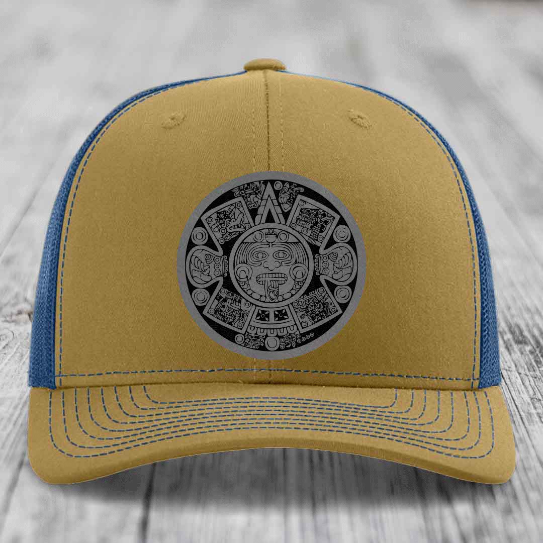 Tan and blue trucker hat with Aztec calendar patch on front.