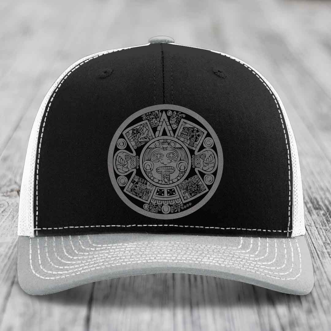 Black and grey trucker hat with Aztec calendar design on front.
