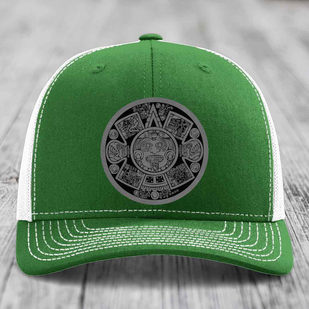 Green trucker hat with white mesh back and gray Aztec calendar patch on front.