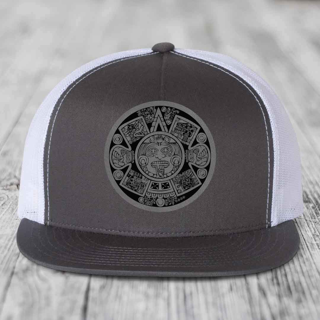 Grey and white trucker hat with Aztec calendar patch on front.