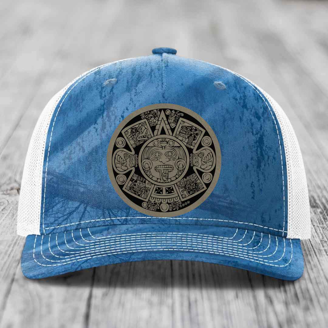 Blue and white trucker hat with an Aztec calendar leather patch on the front.