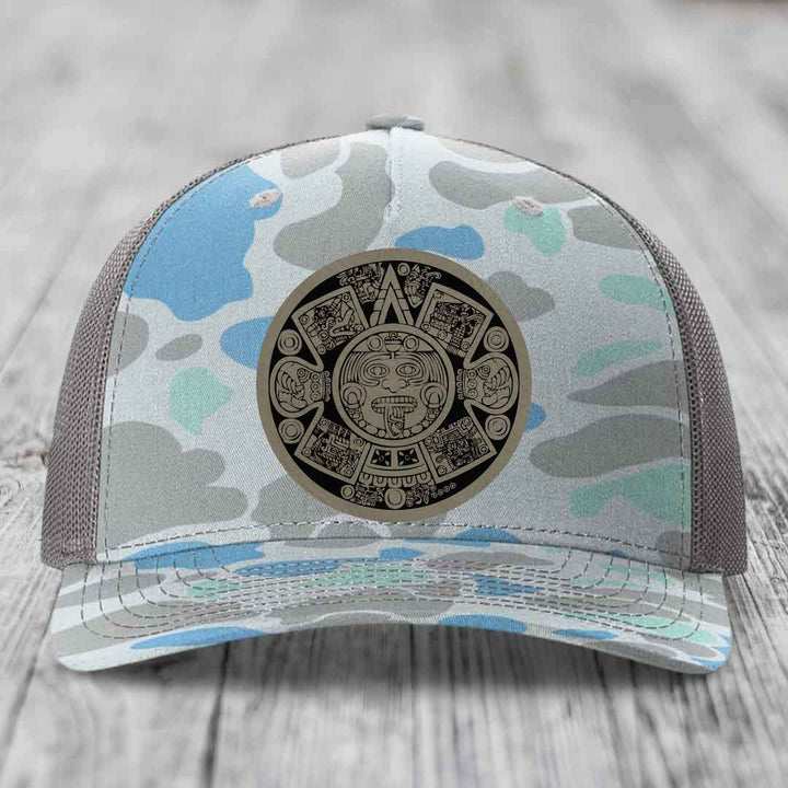 Camouflage trucker hat with Aztec calendar leather patch on front.