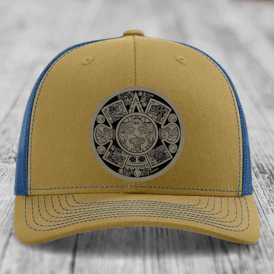 Tan and blue trucker hat with Aztec calendar patch on front.