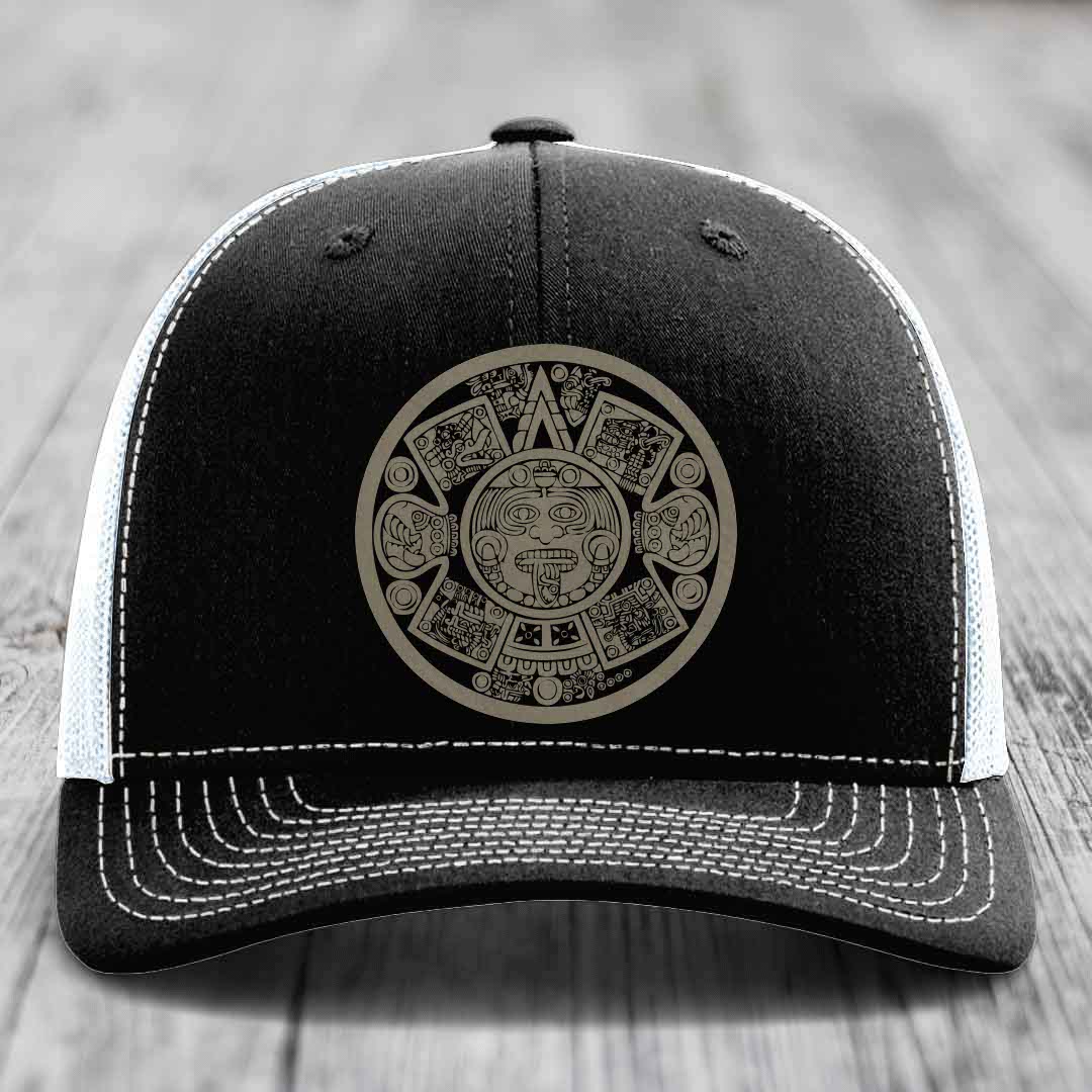 Black trucker hat with white stitching and an Aztec calendar patch on the front.