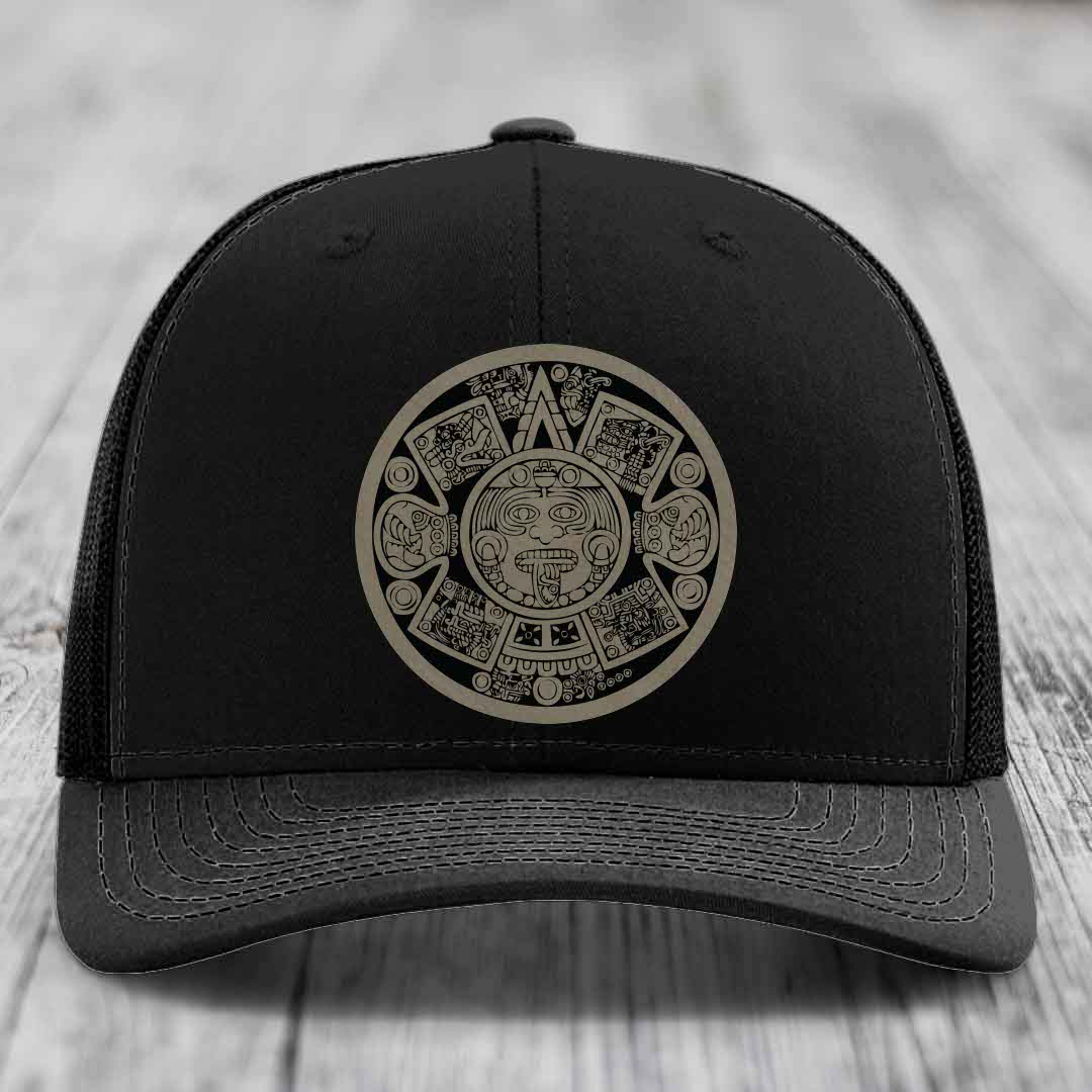 Black trucker hat with Aztec calendar design patch on front.