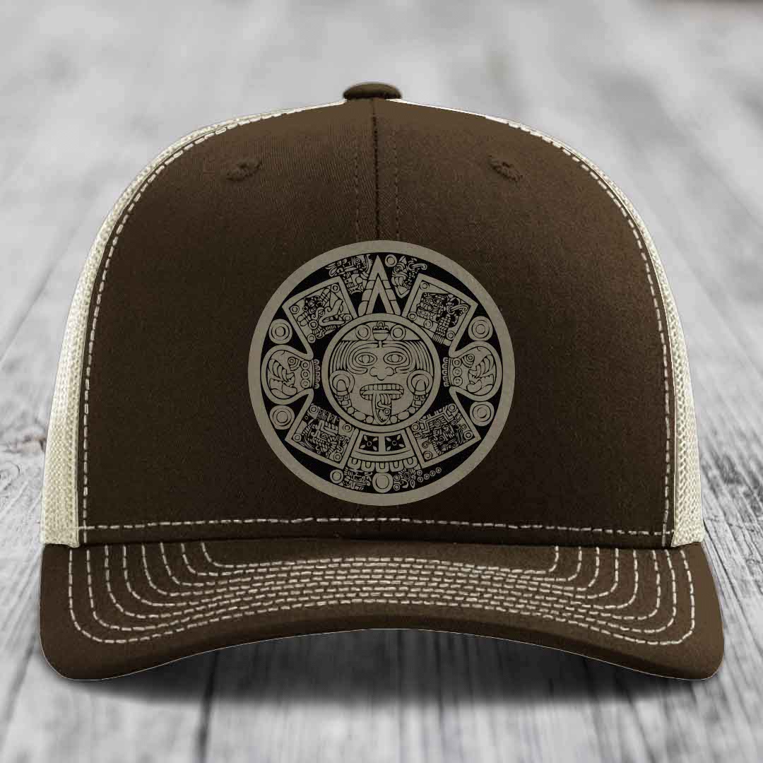 Brown trucker hat with white stitching and an Aztec calendar patch on the front.
