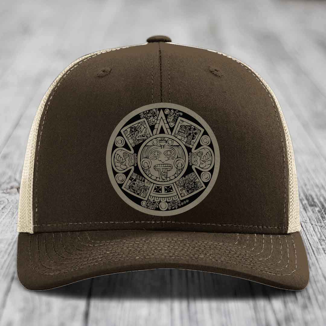 Brown trucker hat with Aztec calendar patch on front, beige mesh back and stitching details.