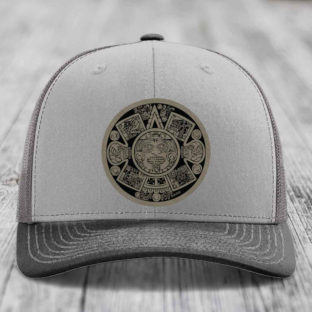 Grey trucker hat with Aztec calendar leather patch on front.