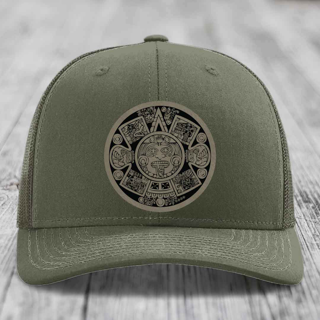 Olive green trucker hat with Aztec calendar patch on front.