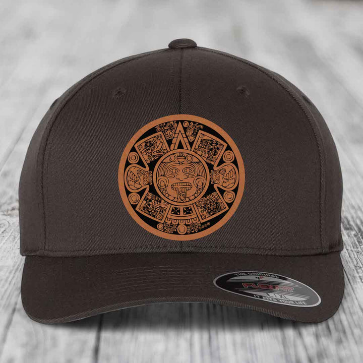 Dark brown baseball cap with Aztec calendar leather patch on front, Flexfit brand label visible.
