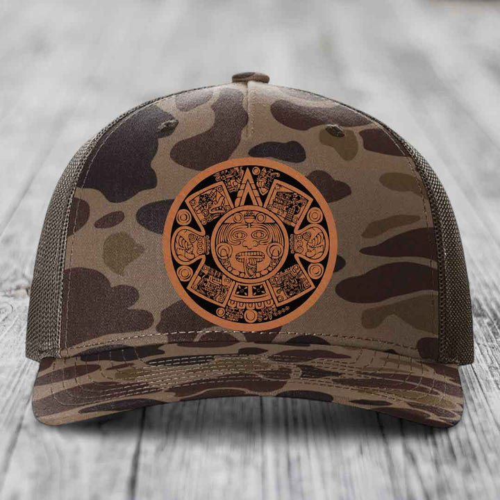 Camouflage trucker hat with Aztec calendar leather patch on front.