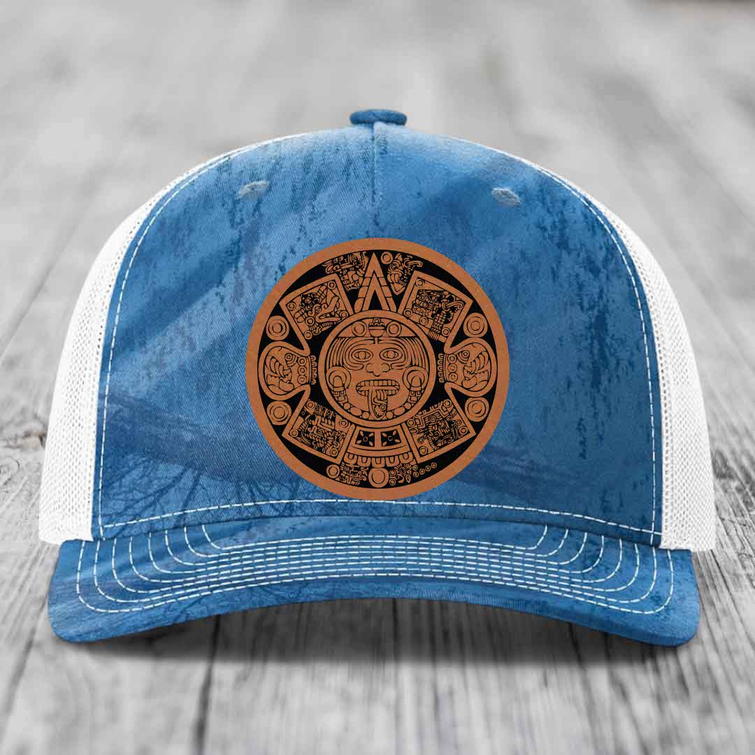 Blue and white trucker hat with a brown Aztec calendar leather patch on the front.