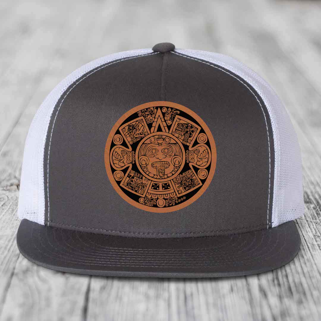 Grey and white trucker hat with brown Aztec calendar leather patch on front.