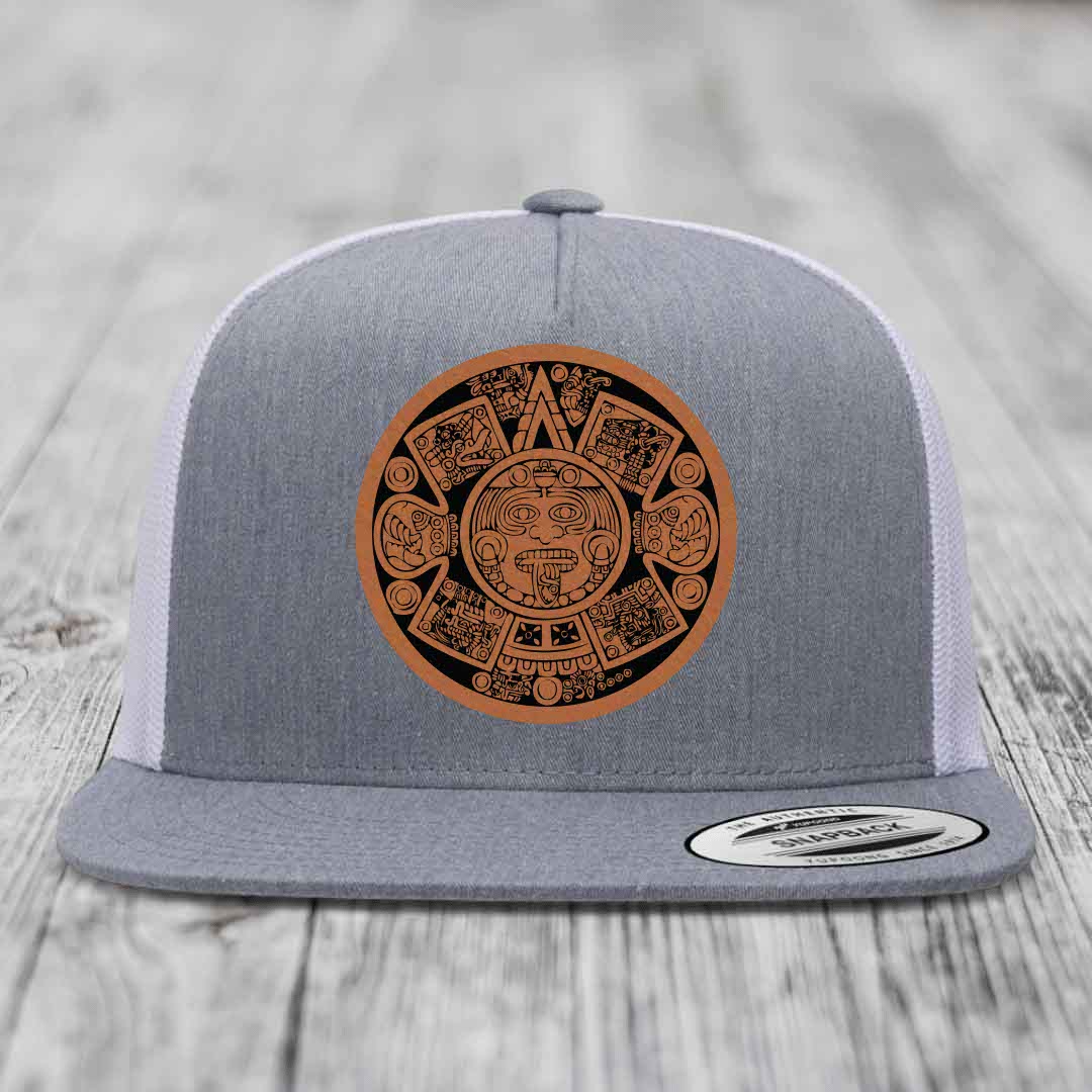 Grey trucker hat with brown Aztec calendar leather patch on front.