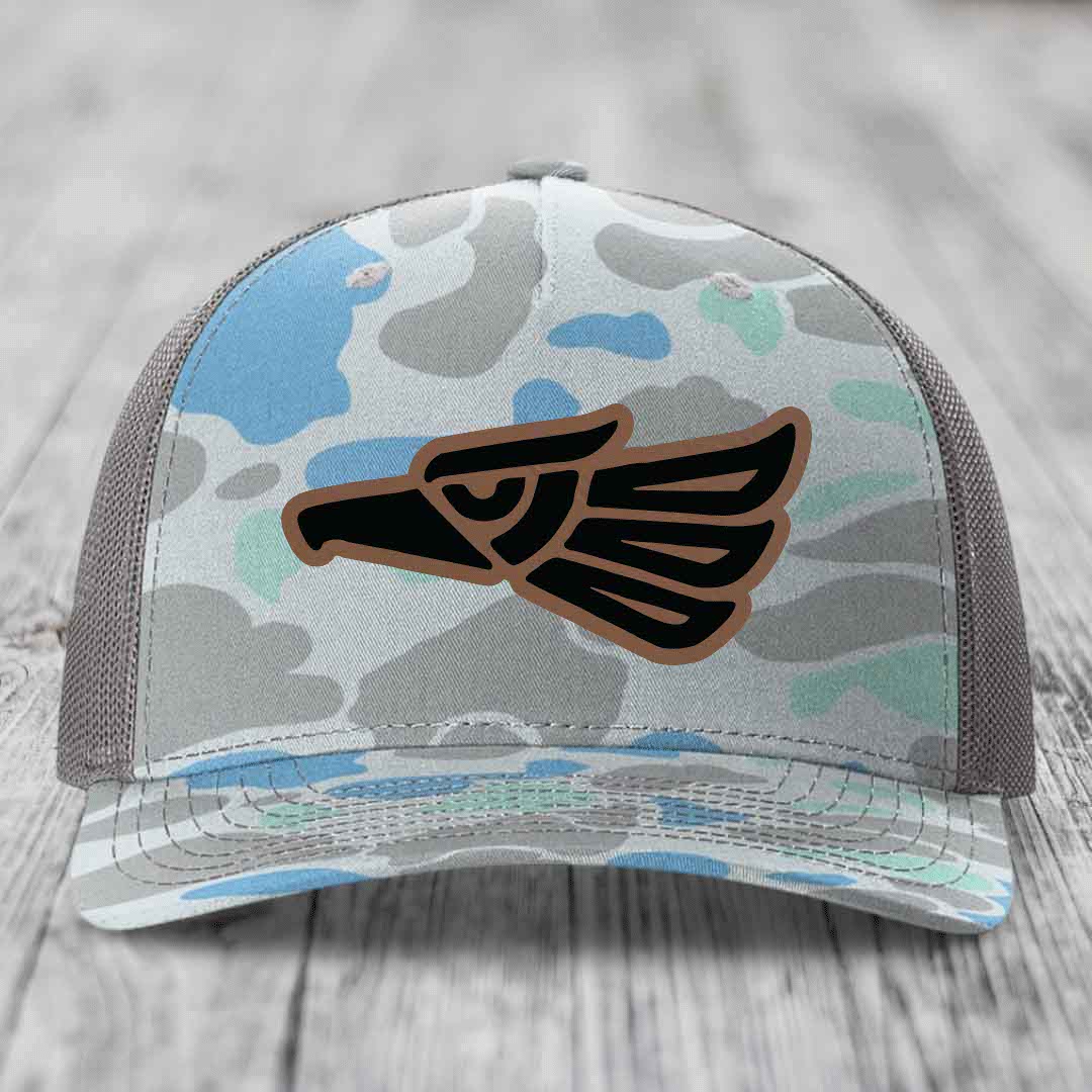Camouflage trucker hat with Aztec eagle leather patch on front.