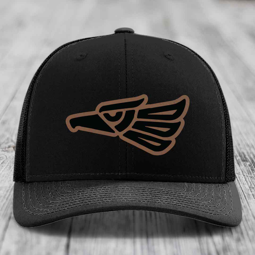 Black trucker hat with brown and black Aztec-style eagle patch on front.