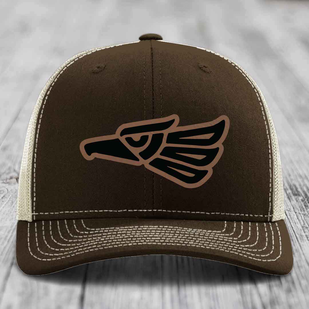 Brown trucker hat with embroidered eagle patch and white stitching on front panel.