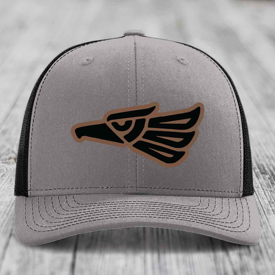 Grey trucker hat with black and brown Aztec eagle leather patch on front.