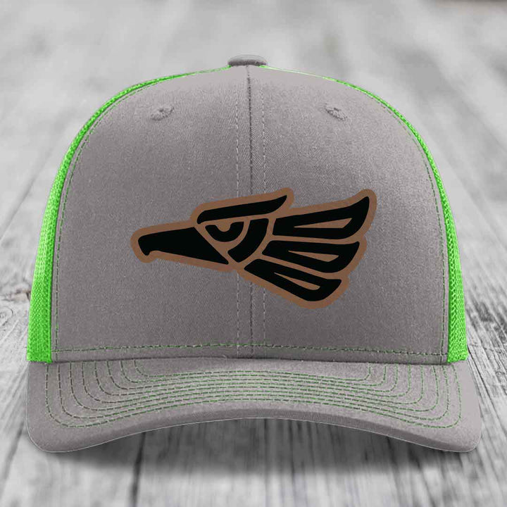 Grey trucker hat with neon green mesh and stitching, featuring a black and brown Aztec eagle leather patch.