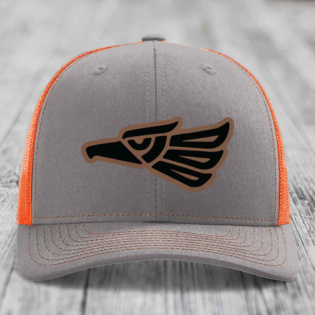 Grey trucker hat with orange mesh back and black eagle patch with brown outline.