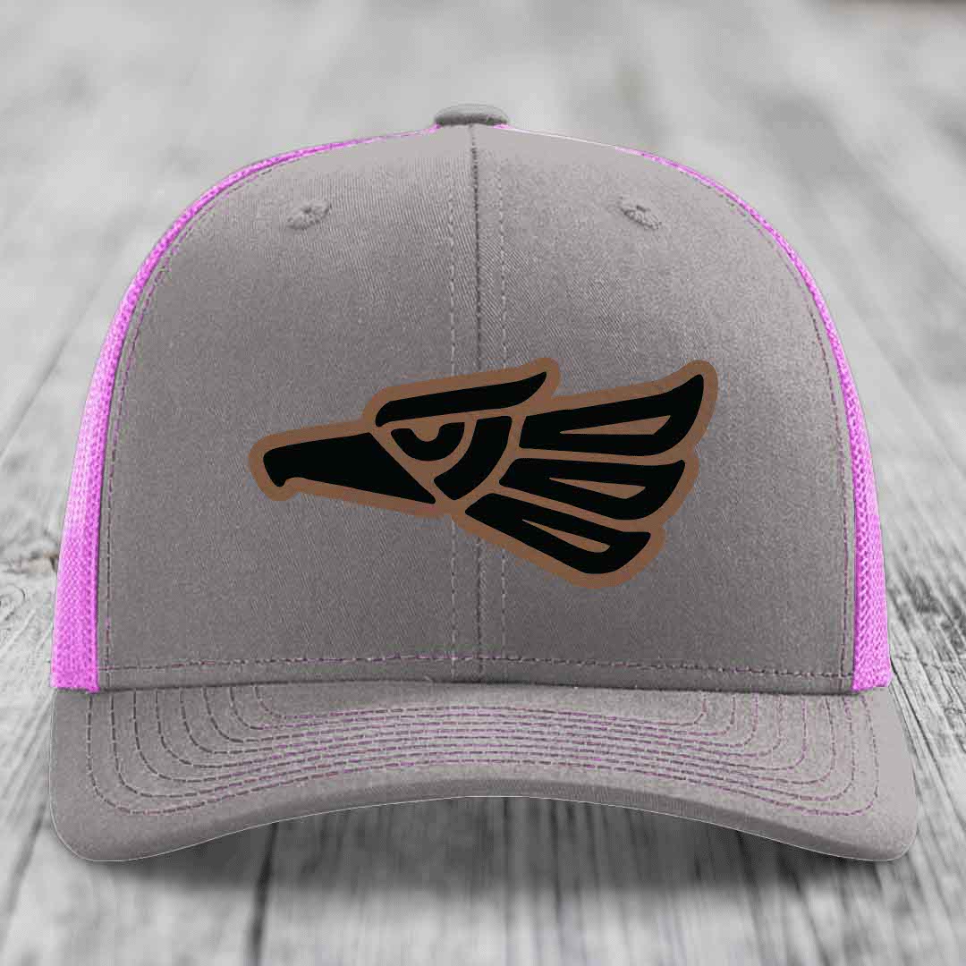 Grey trucker hat with pink mesh sides and a black Aztec-style eagle patch on front.