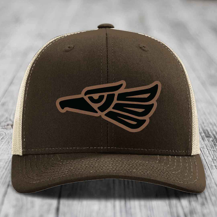 Brown trucker hat with black and tan eagle patch on front, white mesh back.