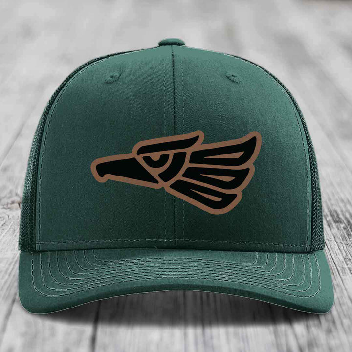 Dark green trucker hat with Aztec-style eagle patch in black and brown.