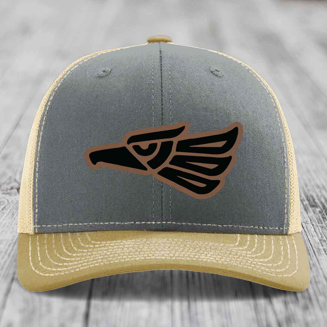 Grey and beige trucker hat with Aztec eagle leather patch on front.