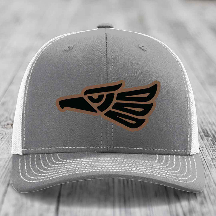 Grey trucker hat with black and brown Aztec eagle patch on front.
