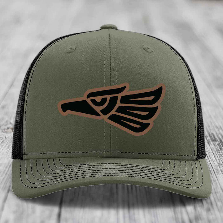 Olive green trucker hat with black and brown Aztec eagle patch on front.