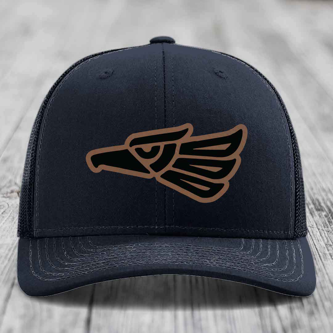 Black trucker hat with brown and black Aztec-style eagle patch on front.