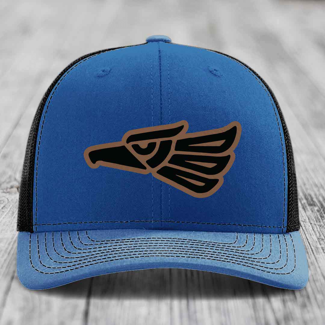 Blue trucker hat with black and brown Aztec eagle patch on front.