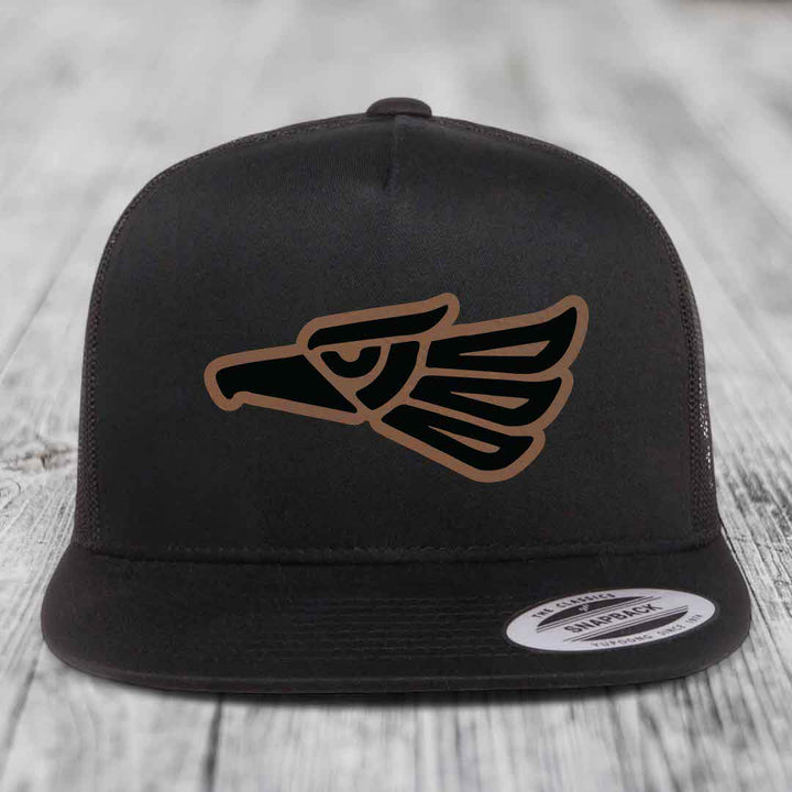 Black trucker hat with Aztec-style eagle patch in black and brown.