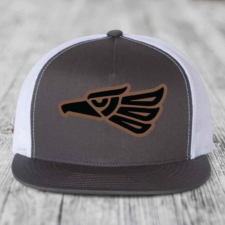 Grey trucker hat with black and brown Aztec eagle patch on front.
