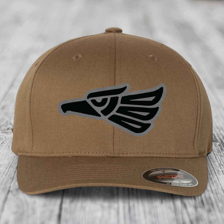 Tan baseball cap with black and grey Aztec eagle patch on front, Flexfit brand label visible.