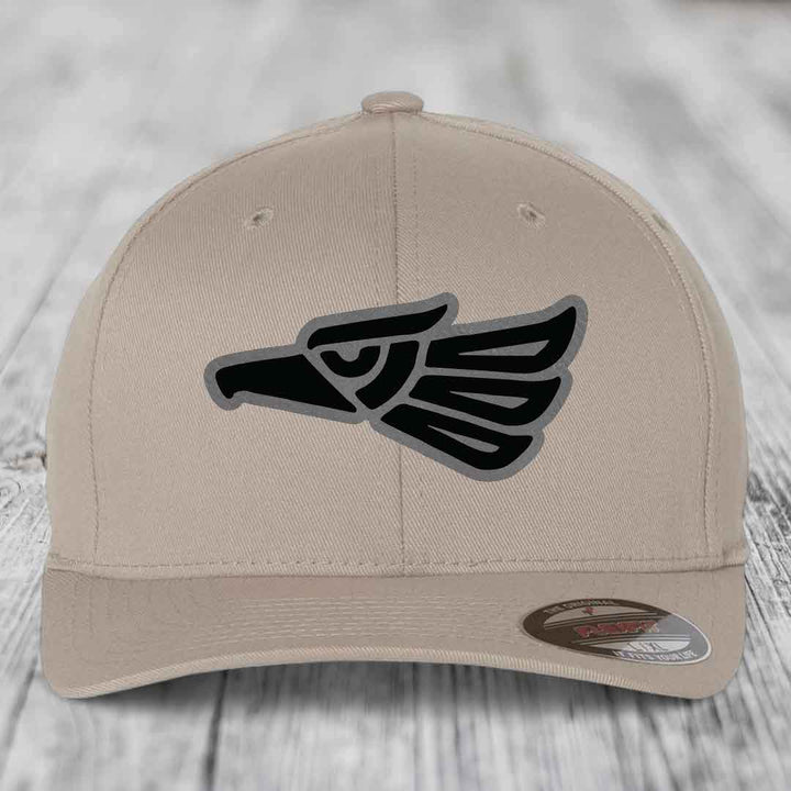 Beige baseball cap with black and grey Aztec eagle patch on front.