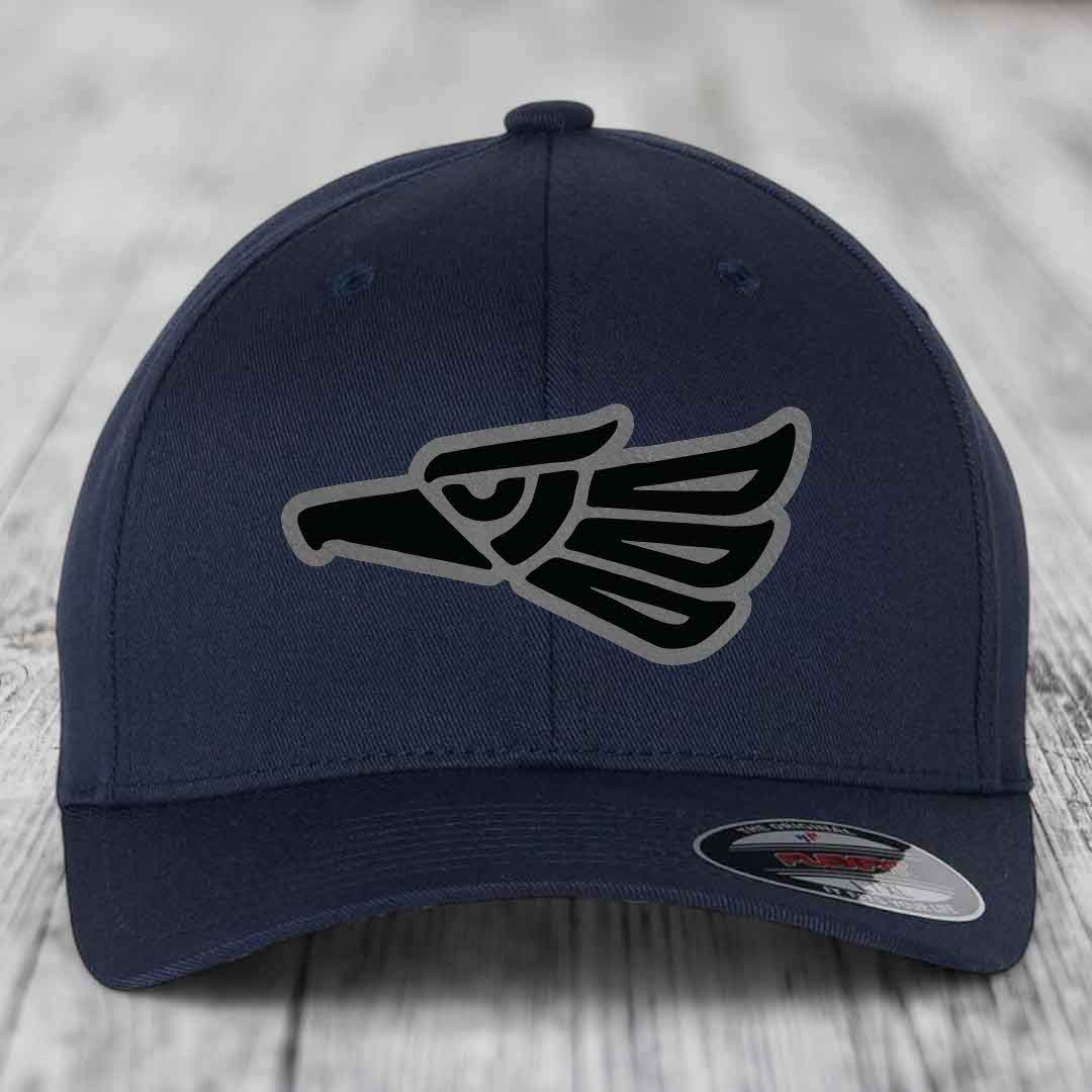 Dark blue baseball cap with embroidered Aztec eagle patch on front, displayed on wooden surface.
