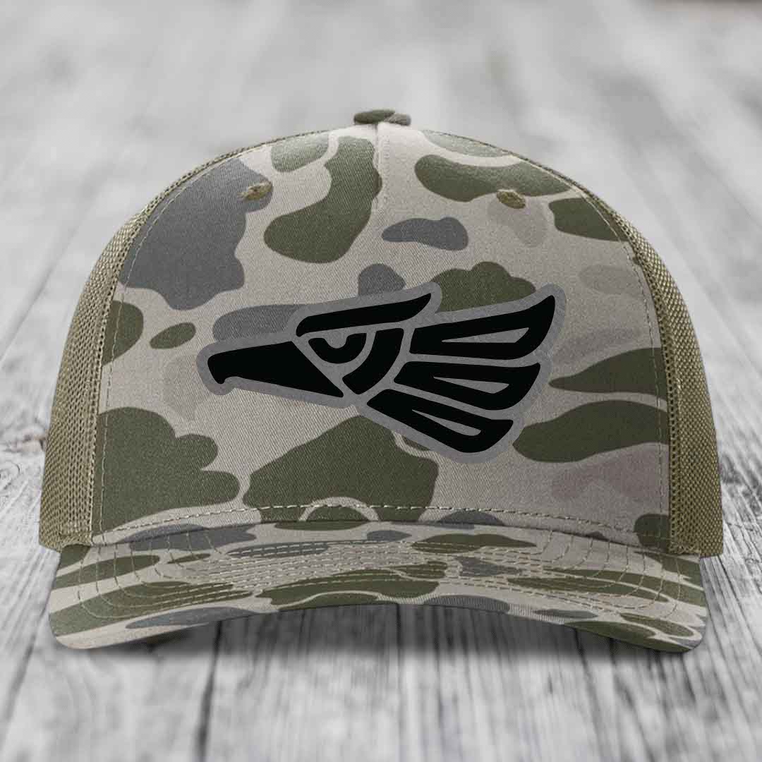 Camouflage trucker hat with black eagle patch on front, olive green mesh back.