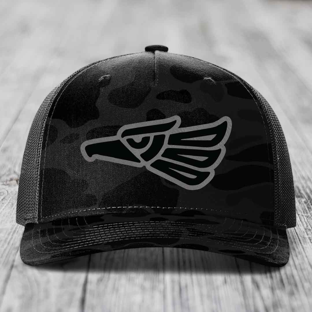 Black camouflage trucker hat with grey Aztec eagle patch on front.