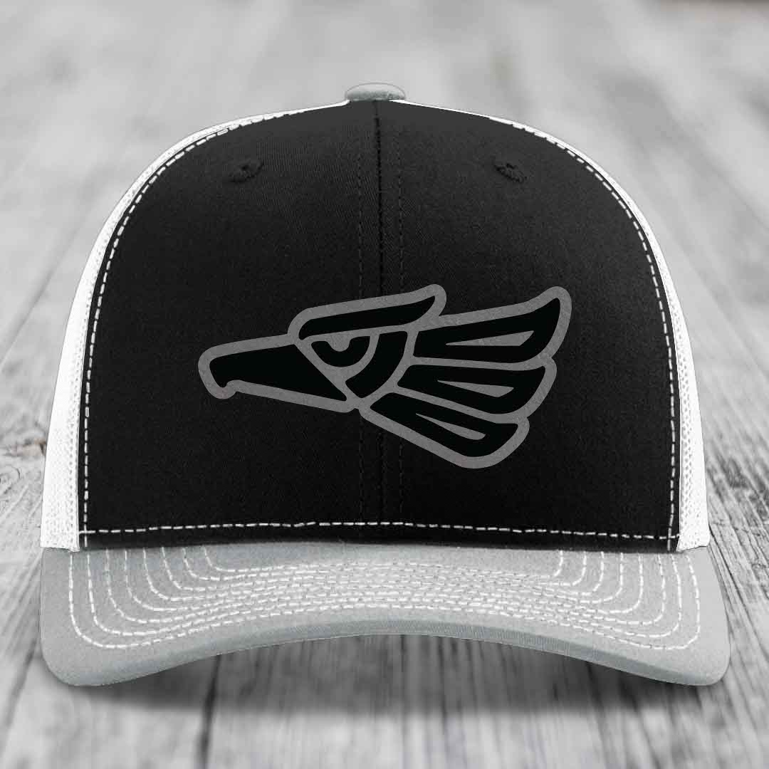 Black and white trucker hat with grey stitching and an Aztec-style eagle patch on front.